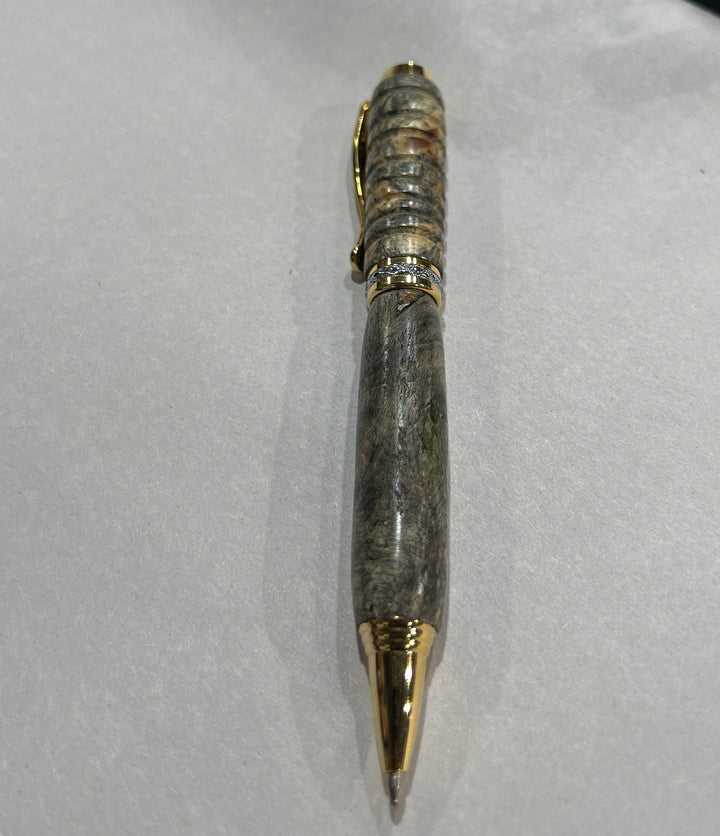 Ball point pen with silver and gold metal  hardware . And buckeye Burl wood . Friction polish.