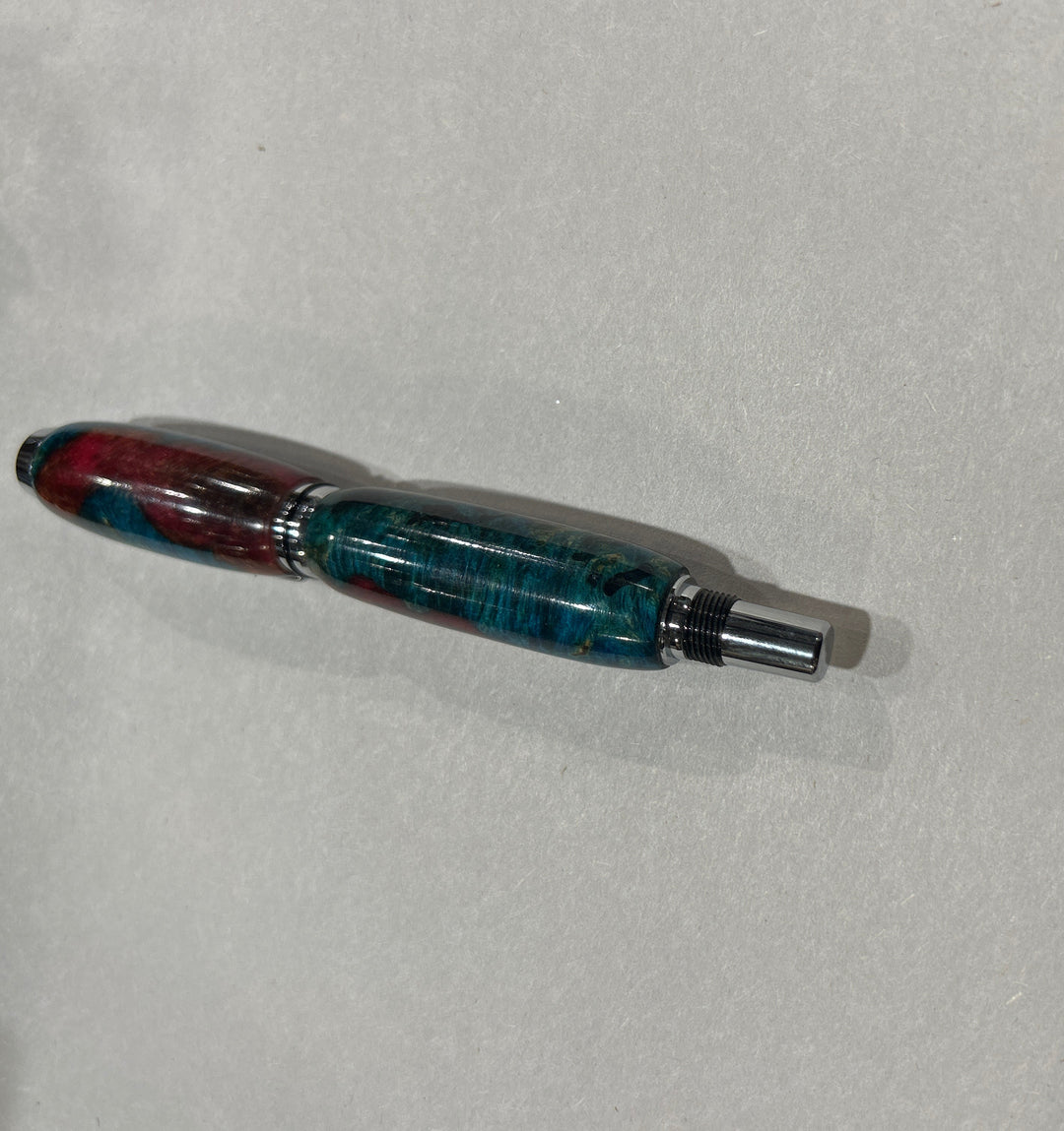 Roller ball pen with silver metal and black hardware with. And blue burl wood with pink little bit of brown acrylic a. CA finish.