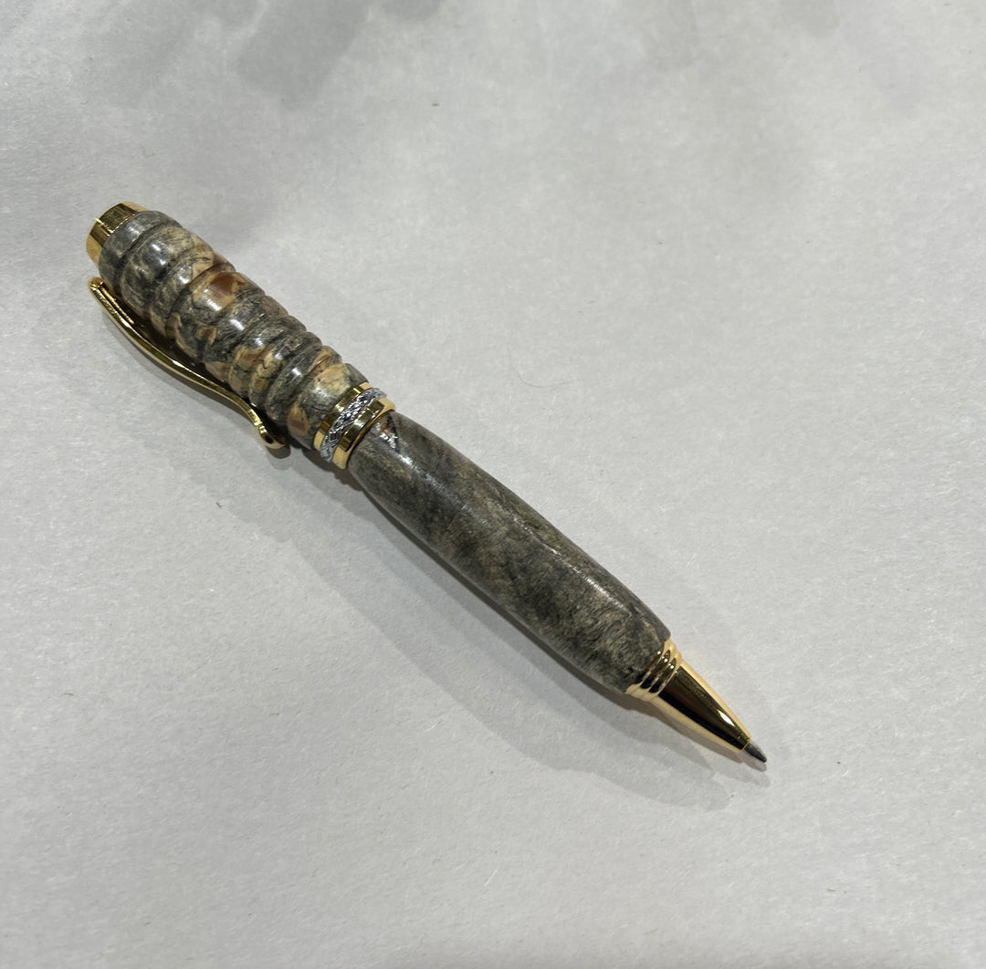 Ball point pen with silver and gold metal  hardware . And buckeye Burl wood . Friction polish.