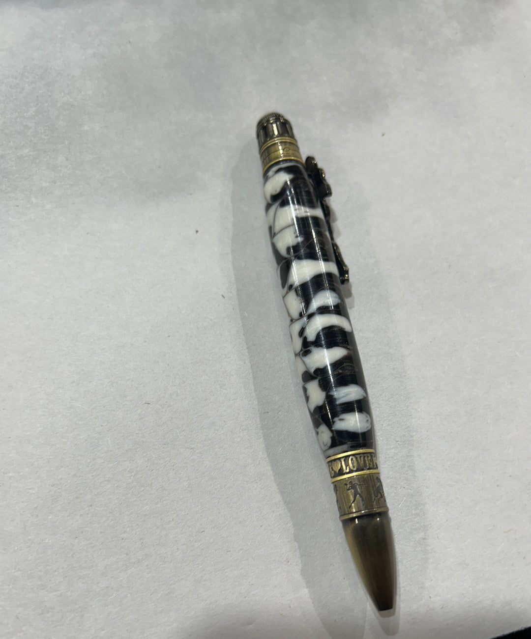 Ball point pen with a bronze metal love football live design, hardware . And a black and white acrylic . friction finish.