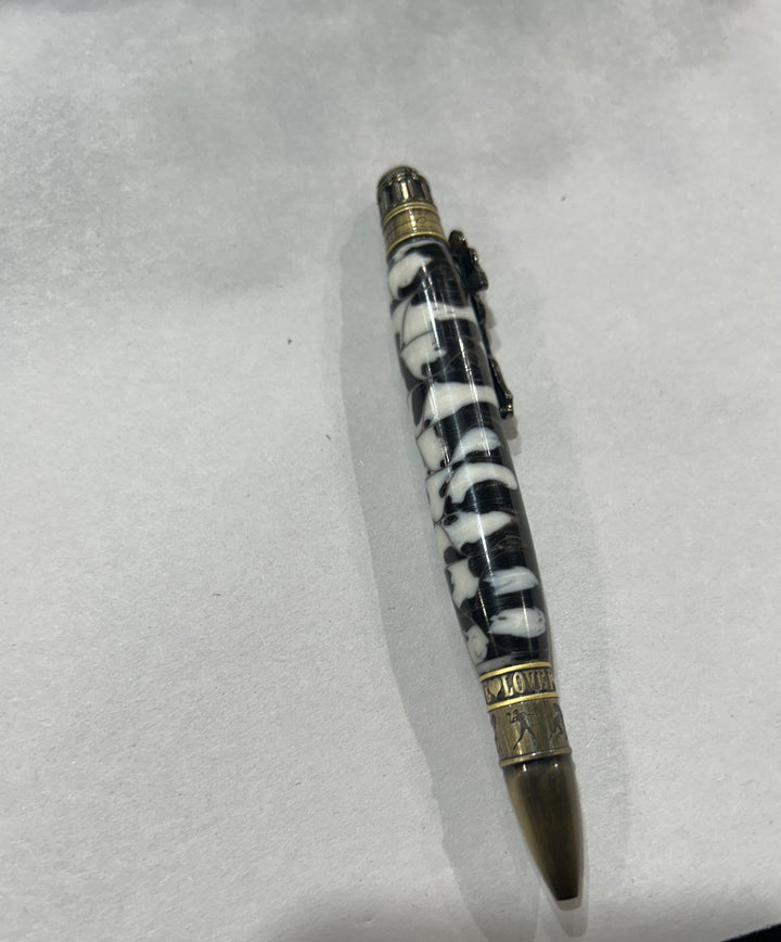 Ball point pen with a bronze metal love football live design, hardware . And a black and white acrylic . friction finish.