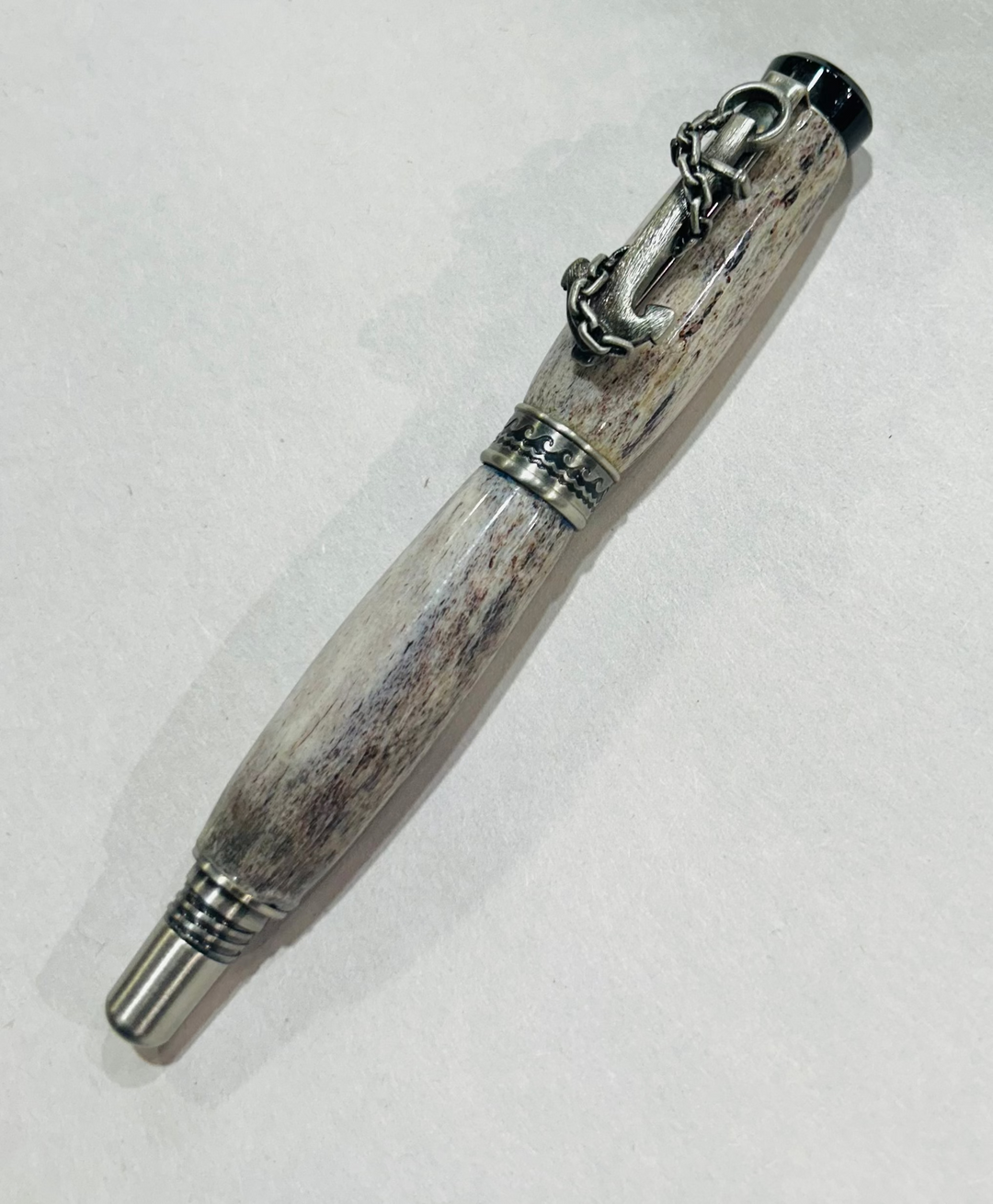 Roller ball pen with a brush nickel, metal and black hardware with ocean themed. And deer antler. CA finish.