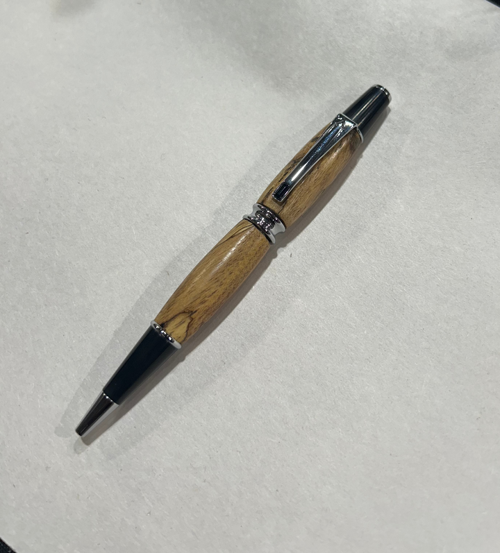 Ball point pen with a Silver metal and black hardware with black last diamond. And a in pecan wood . friction finish.