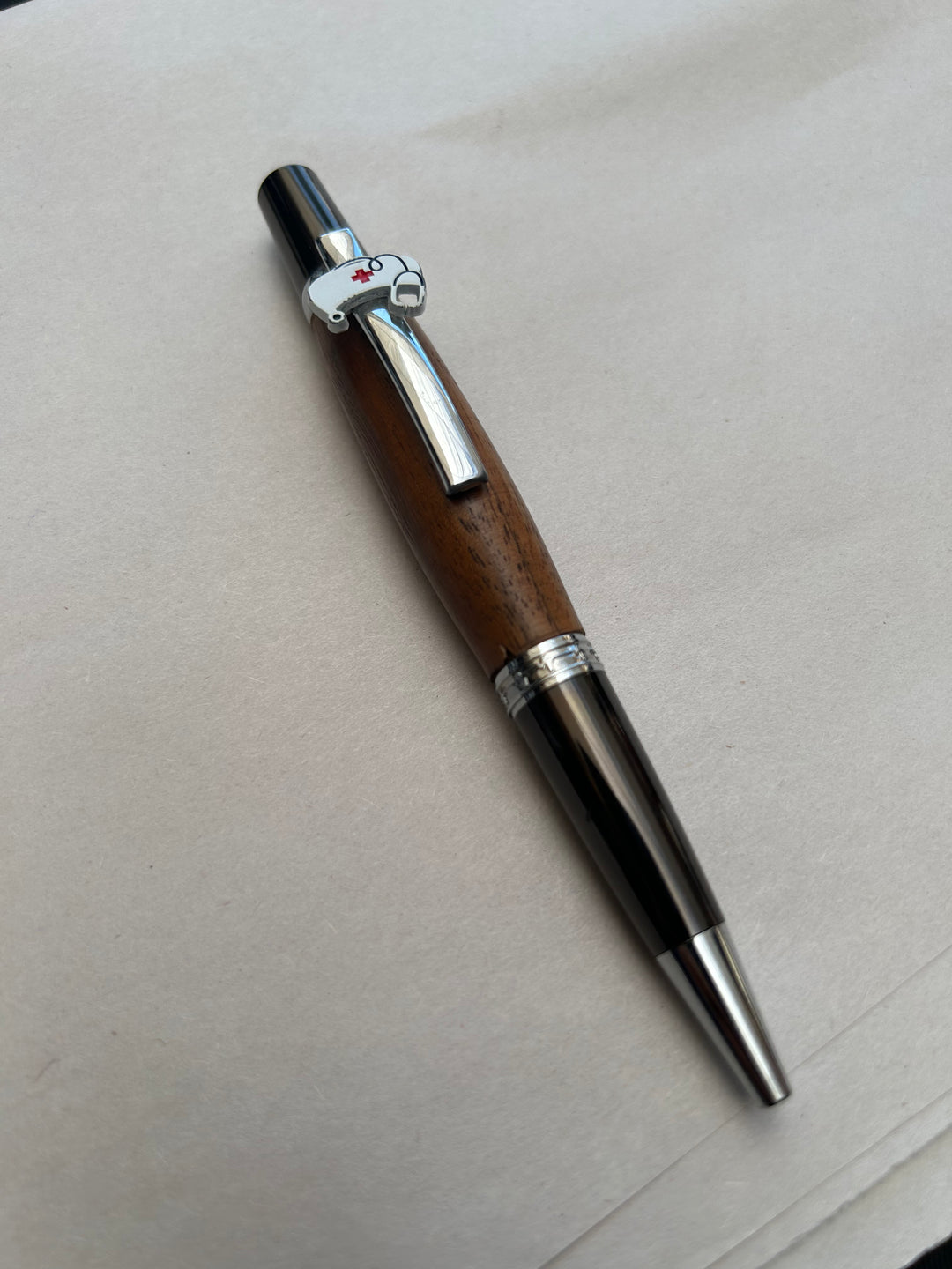 Ball point pen with silver and gun metal  hardware  with the nurse themed peace on it and stylus. And walnut wood. Friction polish.